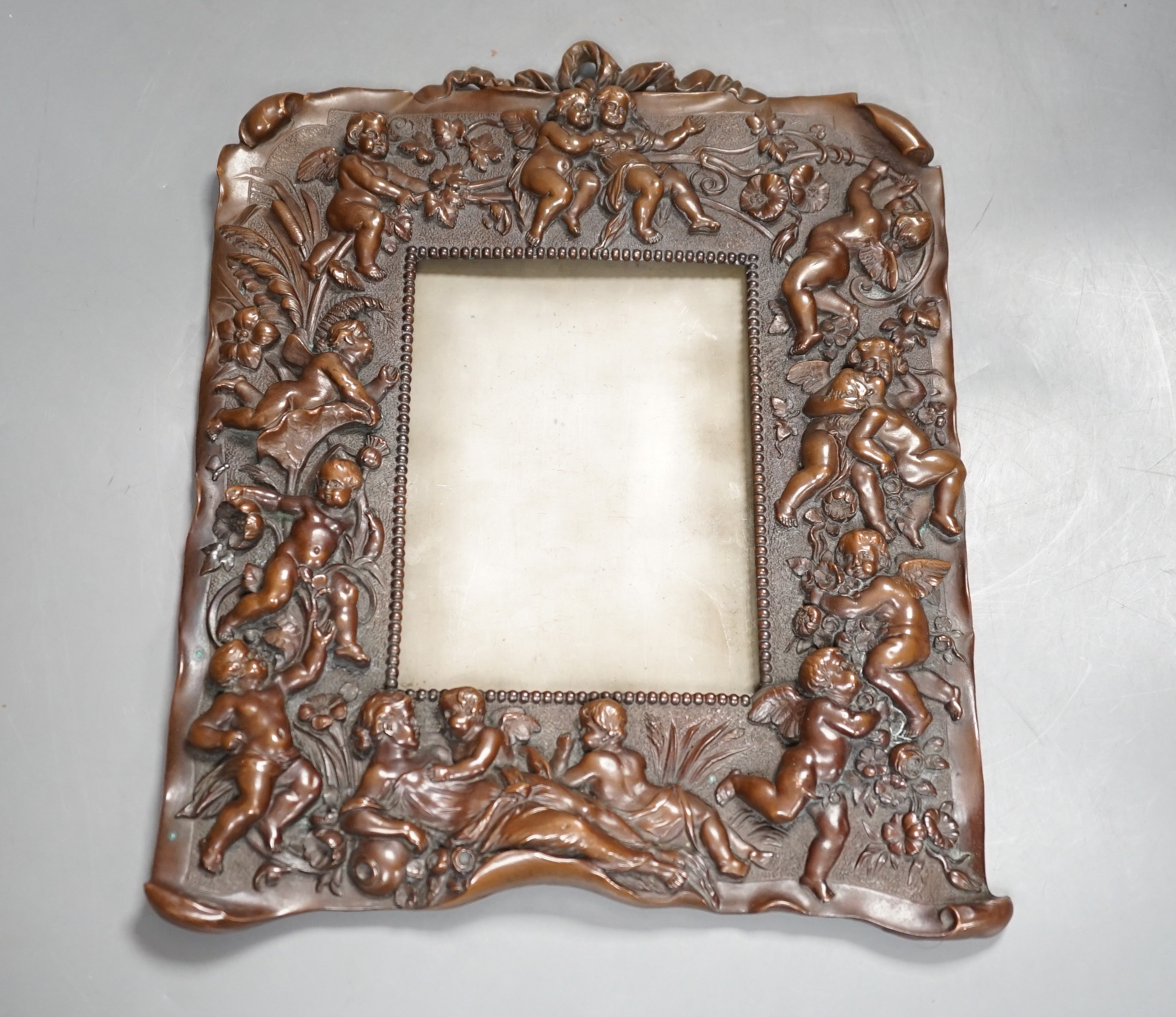 A bronzed copper frame decorated with putti, circa 1900. 28.5cm long